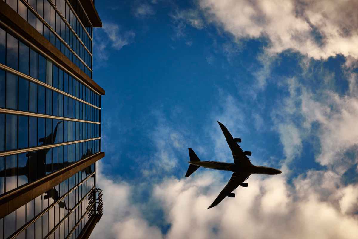 Un aereo nel cielo davanti ad un grattacielo