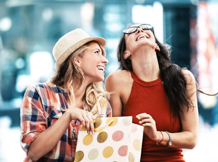 ragazze ridono guardando in un sacchetto dello shopping