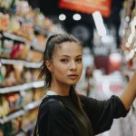 una ragazza fa acquisti scegliendo dallo scaffale di un supermercato