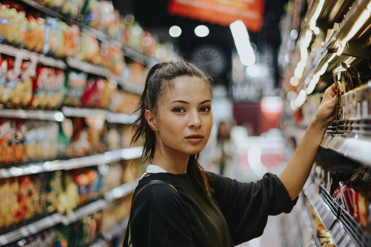 una ragazza fa acquisti scegliendo dallo scaffale di un supermercato