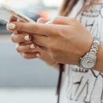 Mani di una ragazza che tengono un cellulare bianco